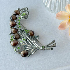 Vintage 1930s floral spray brooch with brown moonglow cabochons and green rhinestones in silver‑tone pot metal.