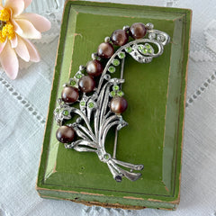 Vintage 1930s floral spray brooch with brown moonglow cabochons and green rhinestones in silver‑tone pot metal.