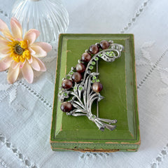 Vintage 1930s floral spray brooch with brown moonglow cabochons and green rhinestones in silver‑tone pot metal.