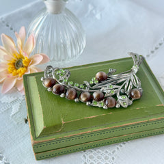 Vintage 1930s floral spray brooch with brown moonglow cabochons and green rhinestones in silver‑tone pot metal.