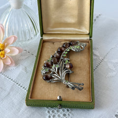 Vintage 1930s floral spray brooch with brown moonglow cabochons and green rhinestones in silver‑tone pot metal.