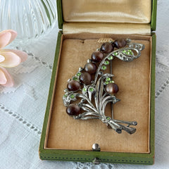 Vintage 1930s floral spray brooch with brown moonglow cabochons and green rhinestones in silver‑tone pot metal.