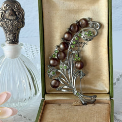 Vintage 1930s floral spray brooch with brown moonglow cabochons and green rhinestones in silver‑tone pot metal.