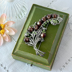 Vintage 1930s floral spray brooch with brown moonglow cabochons and green rhinestones in silver‑tone pot metal.