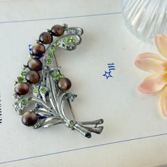 Vintage 1930s floral spray brooch with brown moonglow cabochons and green rhinestones in silver‑tone pot metal.