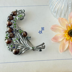 Vintage 1930s floral spray brooch with brown moonglow cabochons and green rhinestones in silver‑tone pot metal.