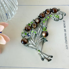 Vintage 1930s floral spray brooch with brown moonglow cabochons and green rhinestones in silver‑tone pot metal.