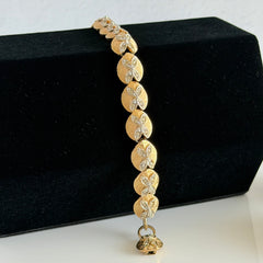Vintage gold tone bracelet with textured links and pavé rhinestone floral accents