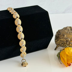 Vintage gold tone bracelet with textured links and pavé rhinestone floral accents