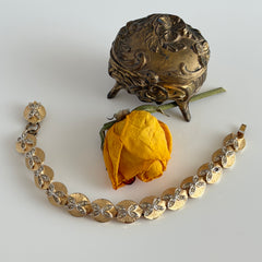 Vintage gold tone bracelet with textured links and pavé rhinestone floral accents