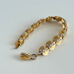 Vintage gold tone bracelet with textured links and pavé rhinestone floral accents