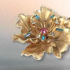 Vintage Bugbee & Niles brushed gold tone flower brooch with pink, aqua, and clear rhinestones, shown from multiple angles to highlight its dimensional petals and detailed construction.
