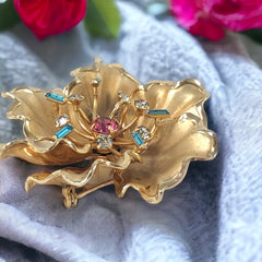 Vintage Bugbee & Niles brushed gold tone flower brooch with pink, aqua, and clear rhinestones, shown from multiple angles to highlight its dimensional petals and detailed construction.