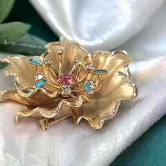 Vintage Bugbee & Niles brushed gold tone flower brooch with pink, aqua, and clear rhinestones, shown from multiple angles to highlight its dimensional petals and detailed construction.