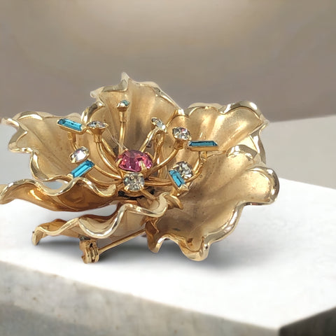 Vintage Bugbee & Niles brushed gold tone flower brooch with pink, aqua, and clear rhinestones, shown from multiple angles to highlight its dimensional petals and detailed construction.