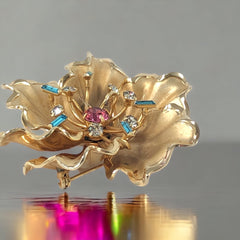 Vintage Bugbee & Niles brushed gold tone flower brooch with pink, aqua, and clear rhinestones, shown from multiple angles to highlight its dimensional petals and detailed construction.