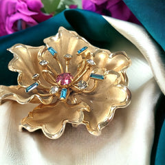 Vintage Bugbee & Niles brushed gold tone flower brooch with pink, aqua, and clear rhinestones, shown from multiple angles to highlight its dimensional petals and detailed construction.