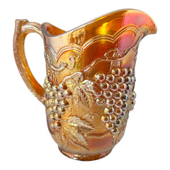 Vintage marigold Carnival Glass pitcher with iridescent grape and leaf pattern, likely Imperial Glass, featuring warm amber, rose, and copper tones; approx. 8¼" tall, in very good condition with minor chips noted on base and rim, ideal for fall decor or vintage display.