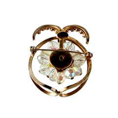 Vintage gold tone brooch featuring a cluster of iridescent aurora borealis crystals framed by curved scrolls and rhinestone accents, shown against various backgrounds.