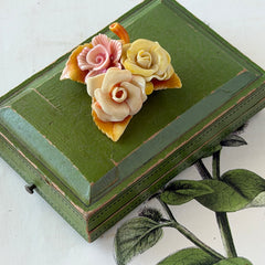 Vintage 1950s celluloid floral brooch with pink, yellow, and cream roses on a single brown leaf, shown from multiple angles.