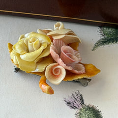 Vintage 1950s celluloid floral brooch with pink, yellow, and cream roses on a single brown leaf, shown from multiple angles.