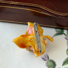Vintage 1950s celluloid floral brooch with pink, yellow, and cream roses on a single brown leaf, shown from multiple angles.