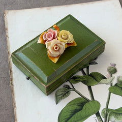 Vintage 1950s celluloid floral brooch with pink, yellow, and cream roses on a single brown leaf, shown from multiple angles.