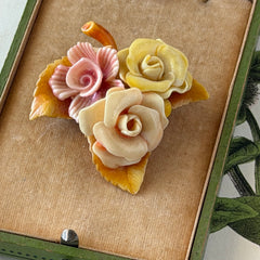 Vintage 1950s celluloid floral brooch with pink, yellow, and cream roses on a single brown leaf, shown from multiple angles.