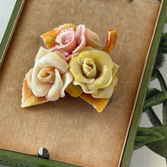 Vintage 1950s celluloid floral brooch with pink, yellow, and cream roses on a single brown leaf, shown from multiple angles.