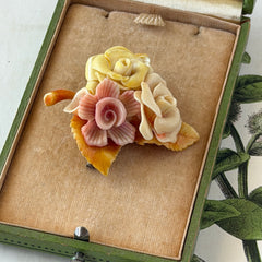 Vintage 1950s celluloid floral brooch with pink, yellow, and cream roses on a single brown leaf, shown from multiple angles.
