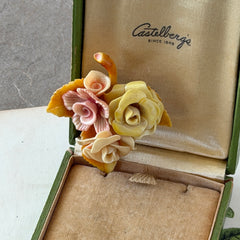 Vintage 1950s celluloid floral brooch with pink, yellow, and cream roses on a single brown leaf, shown from multiple angles.