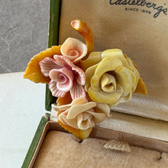 Vintage 1950s celluloid floral brooch with pink, yellow, and cream roses on a single brown leaf, shown from multiple angles.