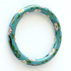 Vintage Chinese turquoise cloisonné bangle with pink and green floral enamel design photographed on linen.
