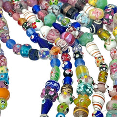 A strand of vintage Chinese lampwork beads from the 1990s, featuring colorful floral and geometric designs in various shapes like oval, cube, and round tube. Each strand includes approximately 20 unique glass beads, new old stock, with a vibrant and playful aesthetic.
