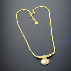 Vintage 1970s Christian Dior necklace featuring a luminous faux pearl pendant accented with pave rhinestones, suspended from a gold plated cobra chain with adjustable spring ring clasp and signed ChrDior © hang tag.