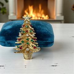 Vintage 1980s gold tone Christmas tree brooch with red, green, and clear rhinestones, featuring a star topper and woven basket base; shown from multiple angles to highlight dimensional detail, condition, and clasp.