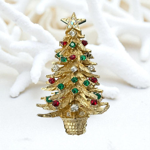 Vintage 1980s gold tone Christmas tree brooch with red, green, and clear rhinestones, featuring a star topper and woven basket base; shown from multiple angles to highlight dimensional detail, condition, and clasp.