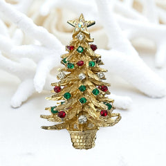 Vintage 1980s gold tone Christmas tree brooch with red, green, and clear rhinestones, featuring a star topper and woven basket base; shown from multiple angles to highlight dimensional detail, condition, and clasp.