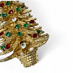 Vintage 1980s gold tone Christmas tree brooch with red, green, and clear rhinestones, featuring a star topper and woven basket base; shown from multiple angles to highlight dimensional detail, condition, and clasp.