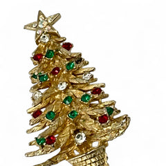 Vintage 1980s gold tone Christmas tree brooch with red, green, and clear rhinestones, featuring a star topper and woven basket base; shown from multiple angles to highlight dimensional detail, condition, and clasp.