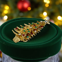 Vintage 1980s gold tone Christmas tree brooch with red, green, and clear rhinestones, featuring a star topper and woven basket base; shown from multiple angles to highlight dimensional detail, condition, and clasp.