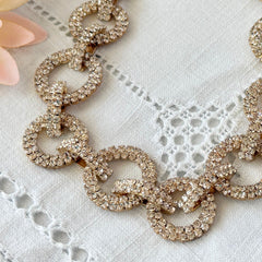 Vintage gold tone necklace with interlocking clear rhinestone circle links and lobster clasp.
