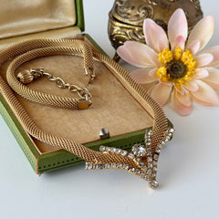 Vintage 1960s gold tone mesh necklace with clear rhinestone centerpiece, shown from multiple angles on display.