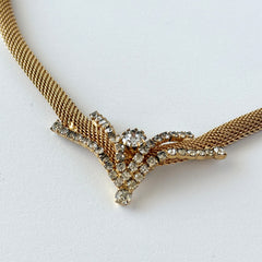 Vintage 1960s gold tone mesh necklace with clear rhinestone centerpiece, shown from multiple angles on display.
