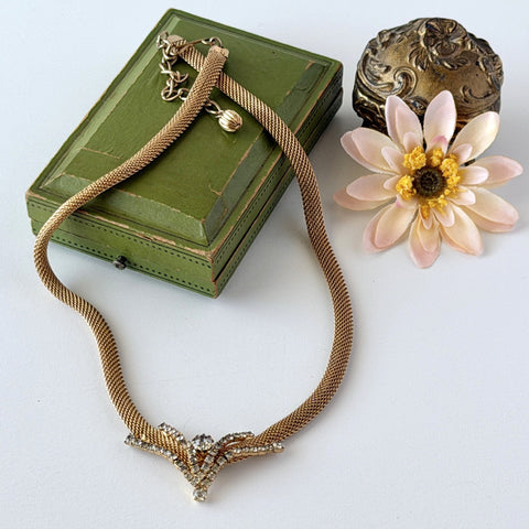 Vintage 1960s gold tone mesh necklace with clear rhinestone centerpiece, shown from multiple angles on display.