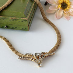 Vintage 1960s gold tone mesh necklace with clear rhinestone centerpiece, shown from multiple angles on display.