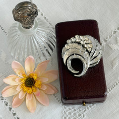 Vintage silver tone swirl leaf brooch with clear rhinestone cluster, textured metal, 1970s–1980s.
