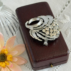 Vintage silver tone swirl leaf brooch with clear rhinestone cluster, textured metal, 1970s–1980s.