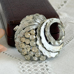 Vintage silver tone swirl leaf brooch with clear rhinestone cluster, textured metal, 1970s–1980s.