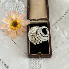 Vintage silver tone swirl leaf brooch with clear rhinestone cluster, textured metal, 1970s–1980s.